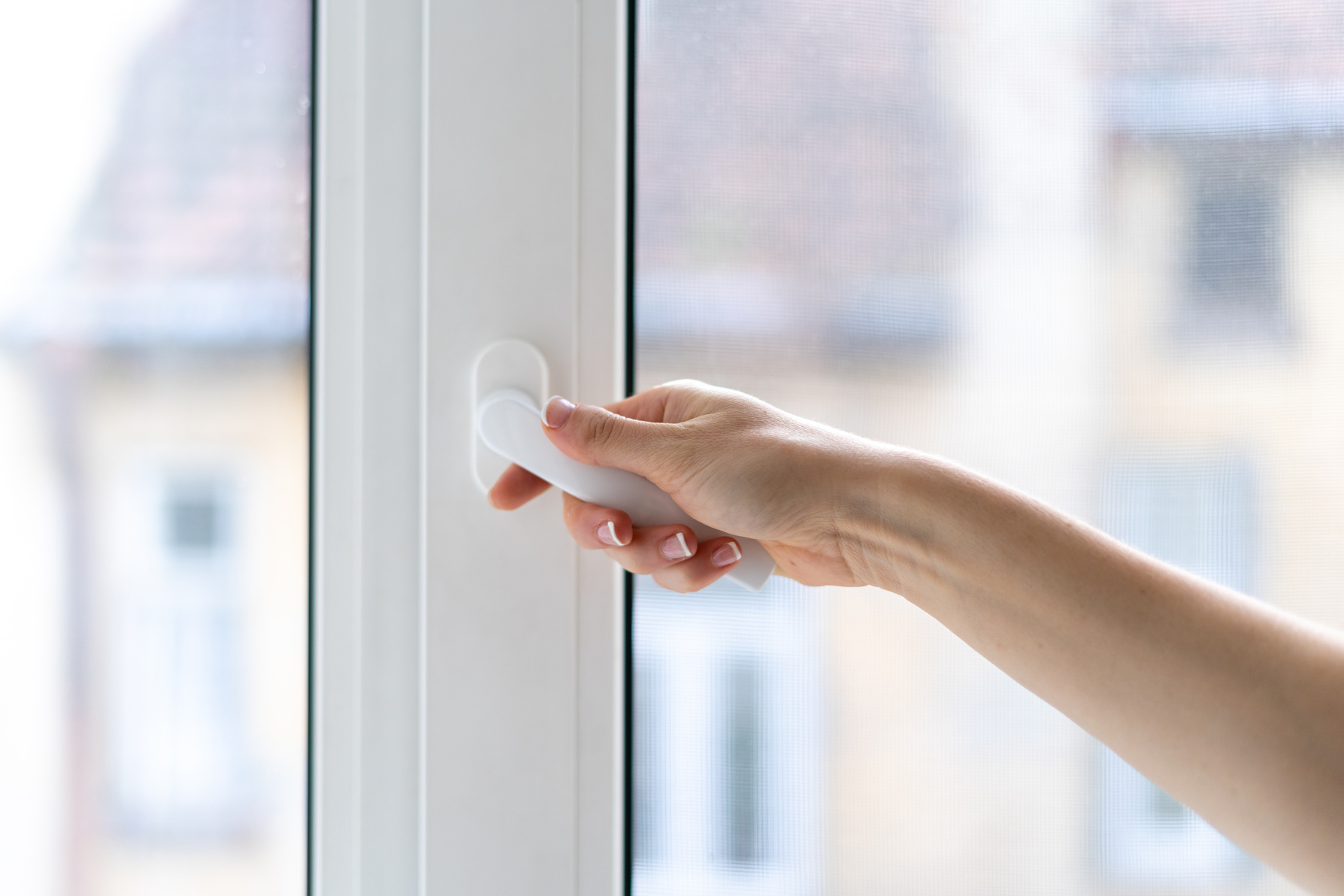 Woman closing pvc window with double glazing